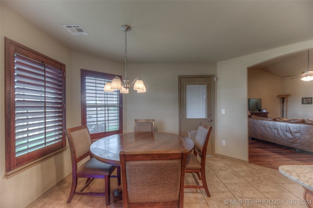 tiled dining space featuring ceiling fan with notable chandelier and a healthy amount of sunlight