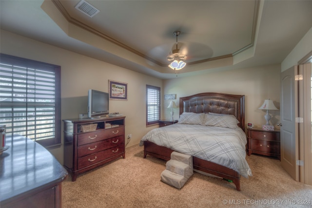 carpeted bedroom with ceiling fan and a tray ceiling