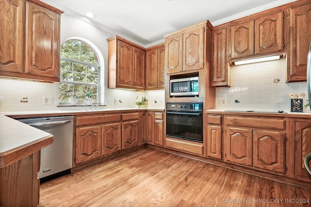 kitchen with light hardwood / wood-style flooring, ornamental molding, and black appliances