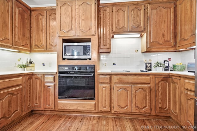 kitchen featuring light wood-type flooring, tasteful backsplash, and black appliances