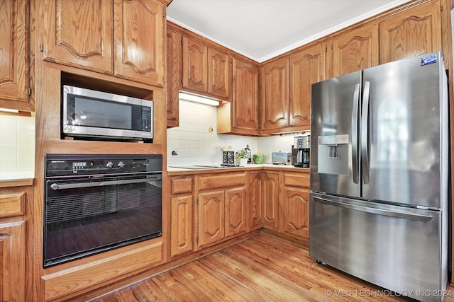 kitchen featuring decorative backsplash, appliances with stainless steel finishes, and light wood-type flooring