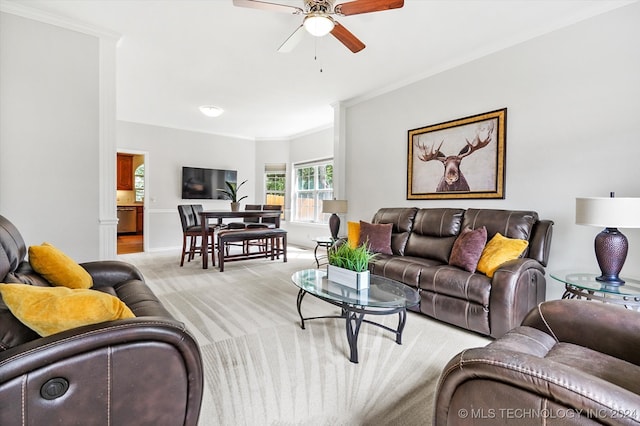 living room with crown molding, ceiling fan, and light colored carpet