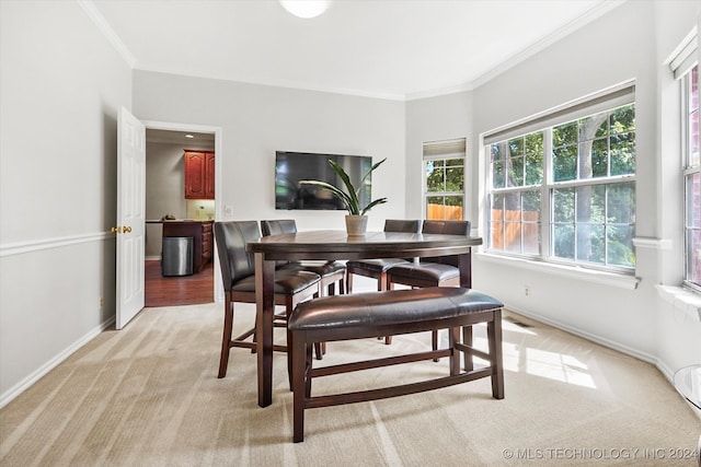 dining space featuring light colored carpet and crown molding