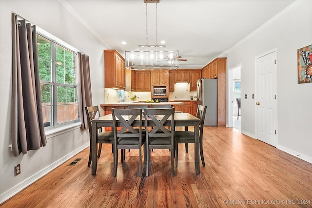 dining space featuring light wood-type flooring, ornamental molding, and an inviting chandelier