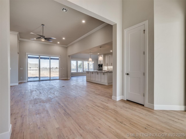 unfurnished living room featuring ornamental molding, ceiling fan, and light hardwood / wood-style flooring