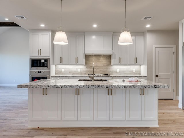 kitchen featuring stainless steel appliances, a kitchen island with sink, and white cabinets