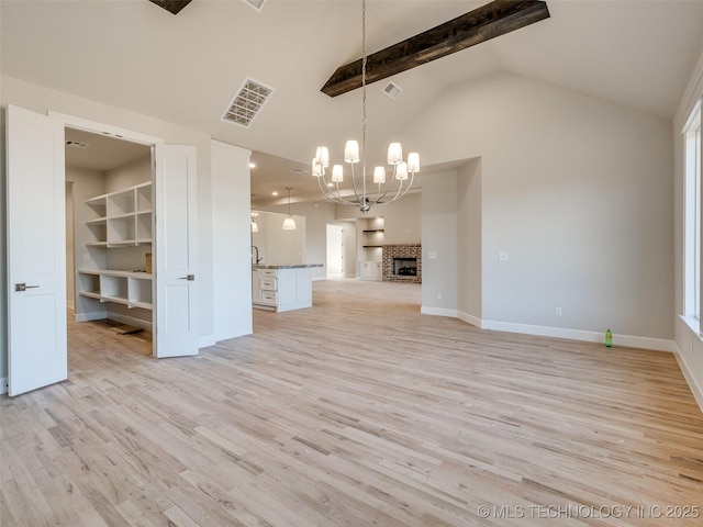 unfurnished living room featuring high vaulted ceiling, beamed ceiling, a chandelier, light hardwood / wood-style floors, and a brick fireplace