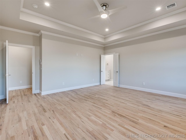 spare room featuring crown molding, light hardwood / wood-style floors, and a tray ceiling