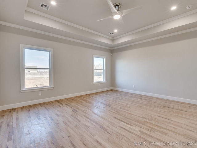 unfurnished room with crown molding, a tray ceiling, ceiling fan, and light wood-type flooring