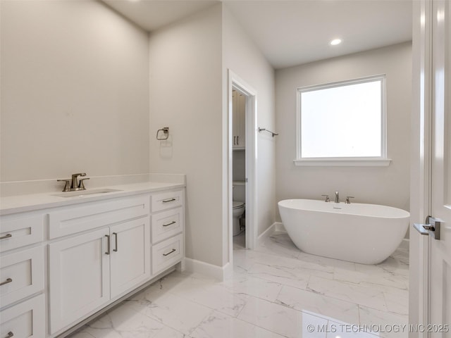 bathroom with vanity, a tub to relax in, and toilet