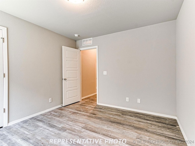 unfurnished room featuring a textured ceiling and light wood-type flooring