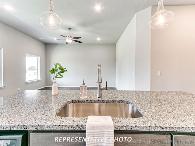 kitchen featuring light stone countertops, ceiling fan, and sink