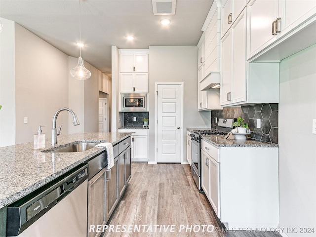 kitchen with light hardwood / wood-style flooring, hanging light fixtures, stainless steel appliances, sink, and white cabinets