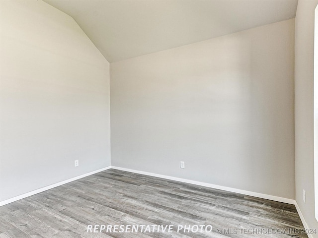 spare room featuring lofted ceiling and hardwood / wood-style flooring