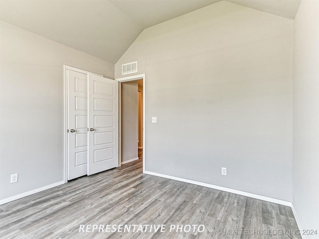 unfurnished bedroom with lofted ceiling and light hardwood / wood-style floors