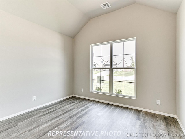 spare room featuring lofted ceiling and hardwood / wood-style floors