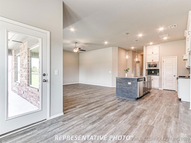 kitchen featuring hanging light fixtures, appliances with stainless steel finishes, white cabinetry, ceiling fan, and a center island with sink