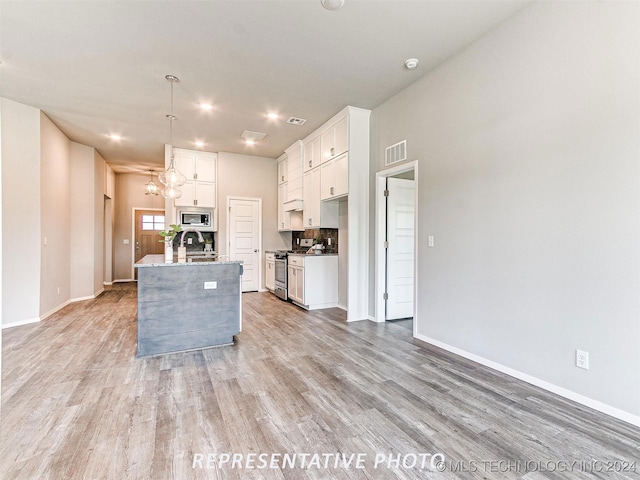 kitchen featuring a chandelier, hanging light fixtures, appliances with stainless steel finishes, white cabinets, and light hardwood / wood-style floors