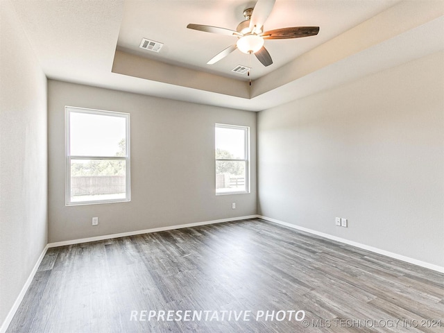 spare room featuring ceiling fan, wood-type flooring, and a tray ceiling