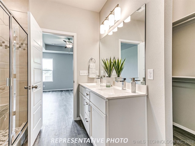 bathroom with hardwood / wood-style floors, ceiling fan, a shower with door, and vanity