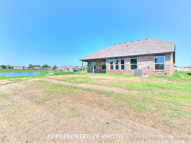 rear view of property with central air condition unit and a yard