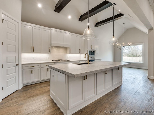 kitchen featuring lofted ceiling with beams, white cabinetry, an island with sink, sink, and hanging light fixtures