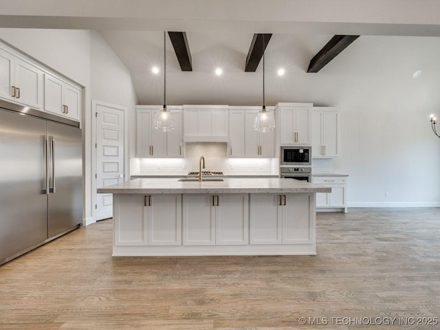 kitchen featuring built in appliances, hanging light fixtures, a center island with sink, beamed ceiling, and white cabinets