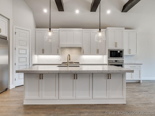 kitchen featuring white cabinetry, decorative light fixtures, an island with sink, and appliances with stainless steel finishes