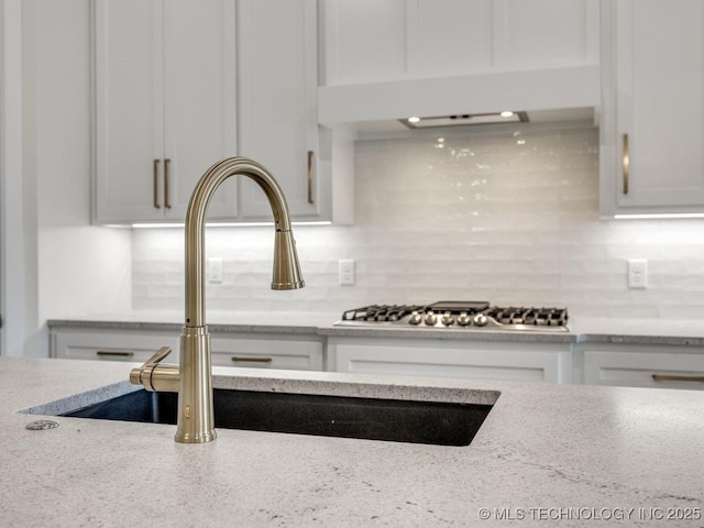 interior details featuring tasteful backsplash, light stone countertops, and white cabinets