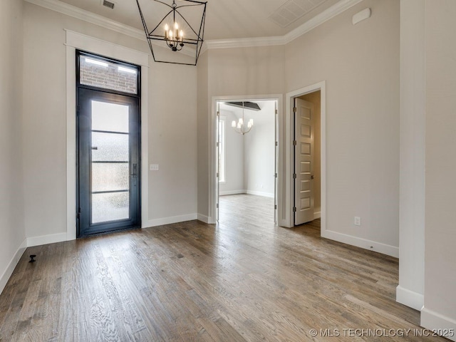 entryway with crown molding, wood-type flooring, and a notable chandelier