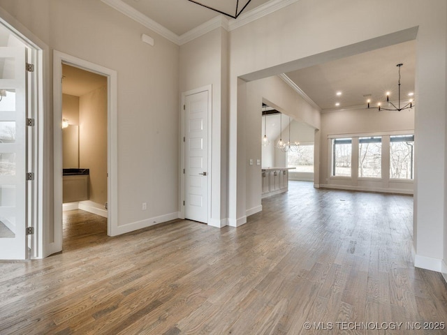 spare room with ornamental molding, wood-type flooring, and a notable chandelier