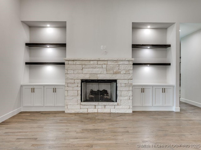 unfurnished living room featuring built in shelves, a fireplace, and light hardwood / wood-style floors