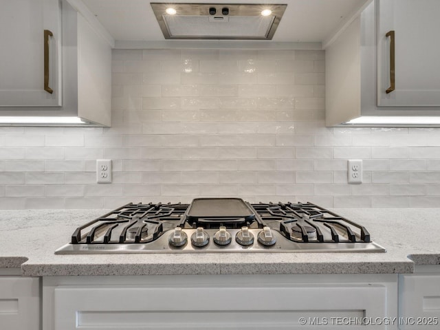 kitchen with stainless steel gas stovetop, ventilation hood, white cabinets, and decorative backsplash