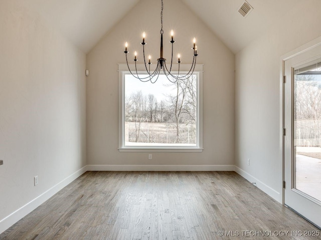 unfurnished dining area featuring lofted ceiling, wood-type flooring, and a notable chandelier