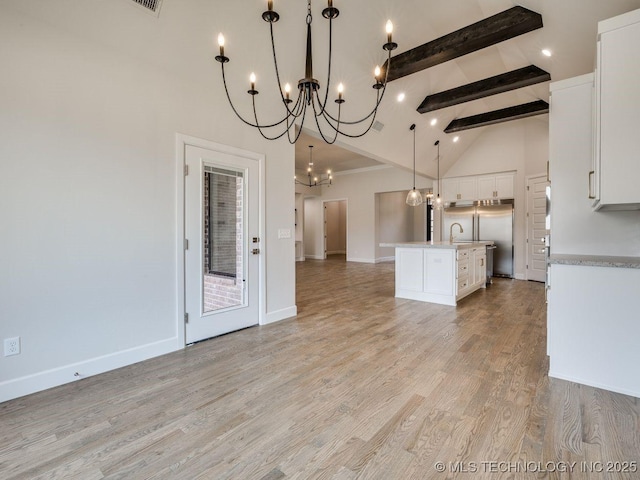 kitchen with white cabinetry, decorative light fixtures, high vaulted ceiling, beam ceiling, and a kitchen island with sink