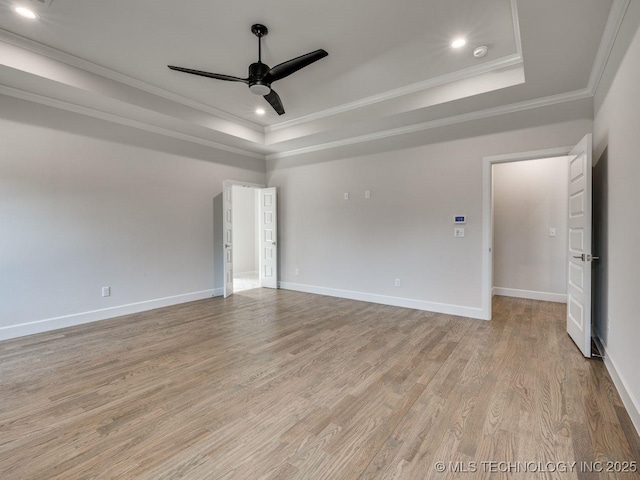 spare room with ceiling fan, ornamental molding, a raised ceiling, and light hardwood / wood-style flooring