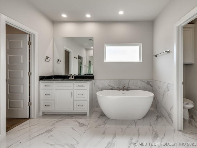 bathroom featuring vanity, a tub, tile walls, and toilet