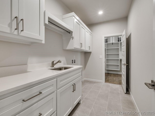 clothes washing area with washer hookup, sink, light tile patterned floors, and cabinets