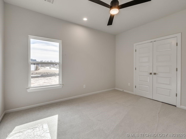 unfurnished bedroom with light colored carpet, ceiling fan, and a closet