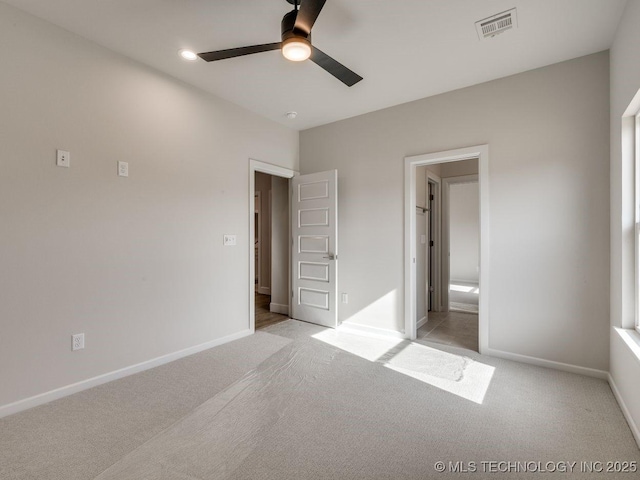 unfurnished bedroom featuring ensuite bathroom, light colored carpet, and ceiling fan