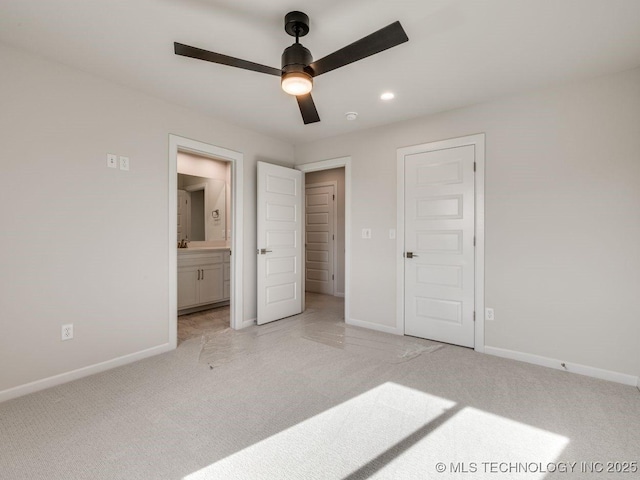 unfurnished bedroom with ensuite bathroom, light colored carpet, and ceiling fan