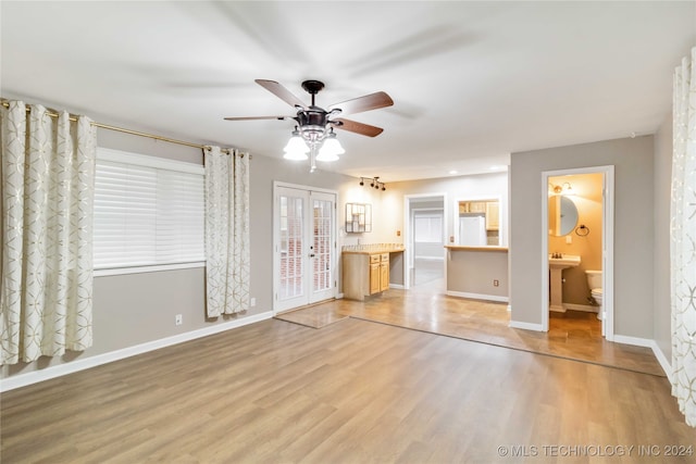 unfurnished living room featuring ceiling fan, french doors, and light hardwood / wood-style floors