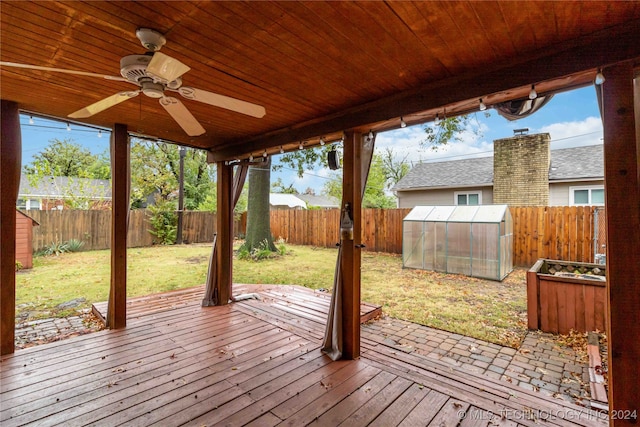 wooden terrace with a storage shed, ceiling fan, and a yard