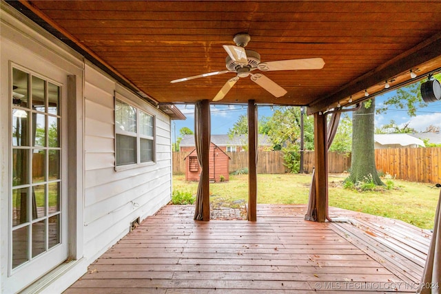 deck with a storage unit, ceiling fan, and a yard