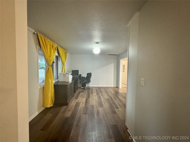 corridor with a textured ceiling and dark hardwood / wood-style flooring