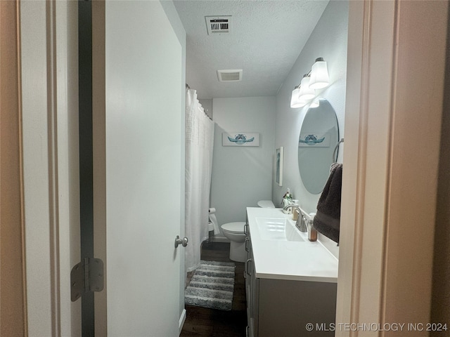 bathroom featuring a textured ceiling, curtained shower, vanity, and toilet