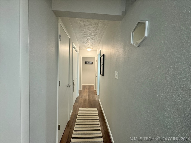 hallway with a textured ceiling and dark hardwood / wood-style flooring