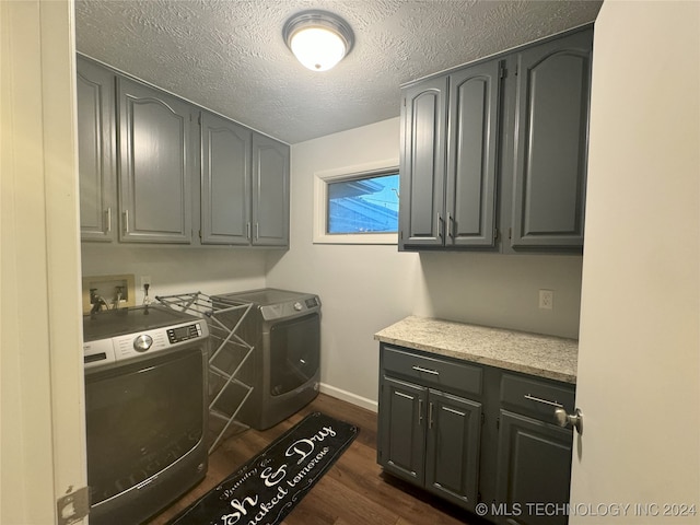 laundry area featuring a textured ceiling, dark wood-type flooring, independent washer and dryer, and cabinets