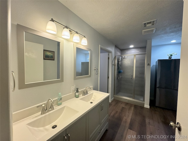 1335 N Mcfarland Pl, Claremore, OK 74017 - bathroom featuring a textured ceiling, double vanity, a shower stall, and wood finished floors