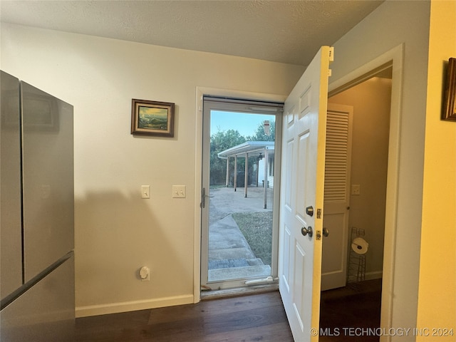 doorway to outside with a textured ceiling and dark hardwood / wood-style floors